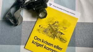 Broschyr och pannlampa på en rutig duk