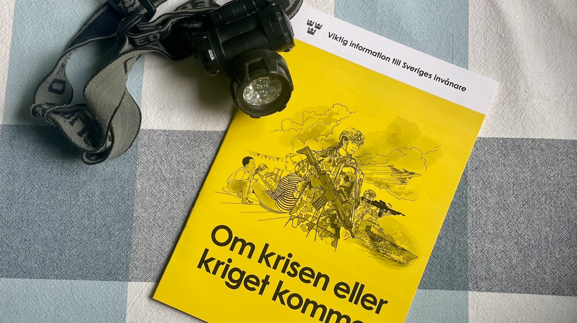 Broschyr och pannlampa på en rutig duk