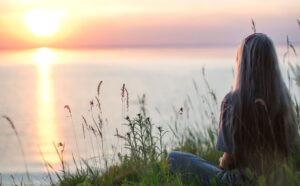 person ser ut över havet och soluppgång
